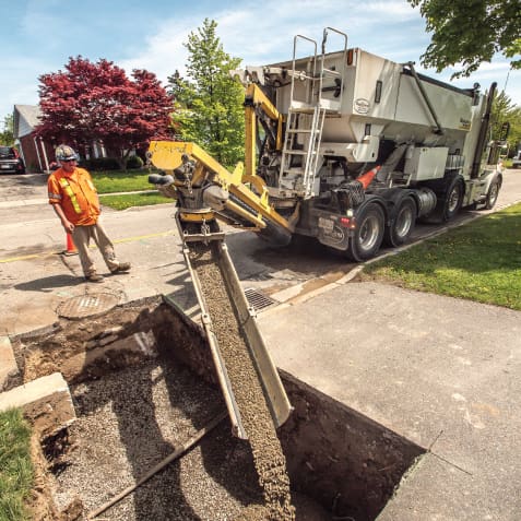 Vacuum excavator and crew working at a trenching and material handling site with active construction equipment.